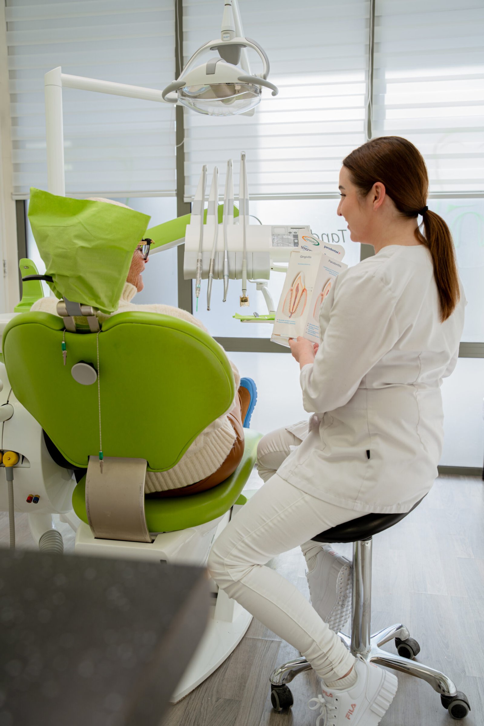 De mondhygiëniste geeft uitleg aan een patiënt in de stoel