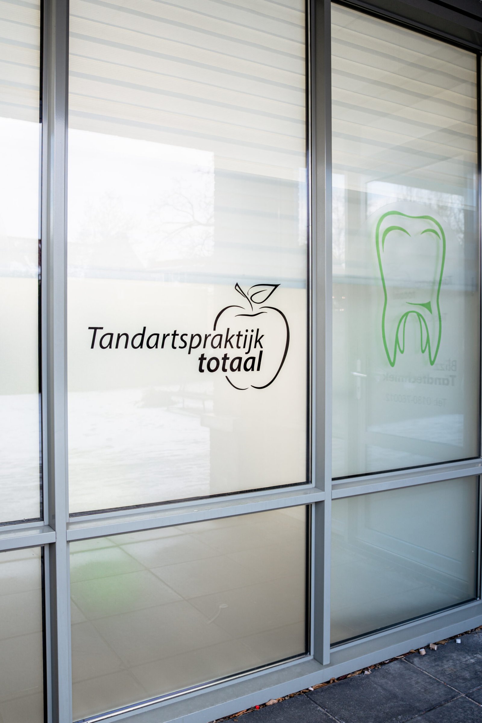 De gevel van de praktijk met het logo op het raam